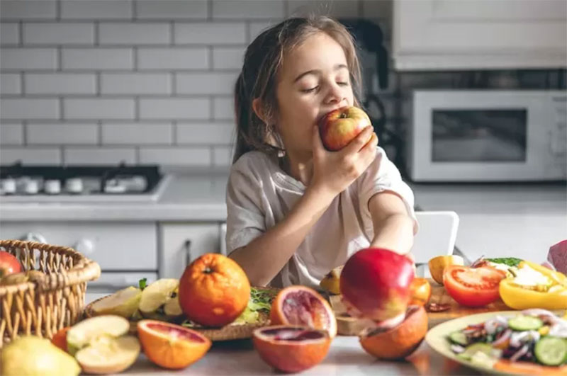 Ilustrasi anak memakan buah apel.
