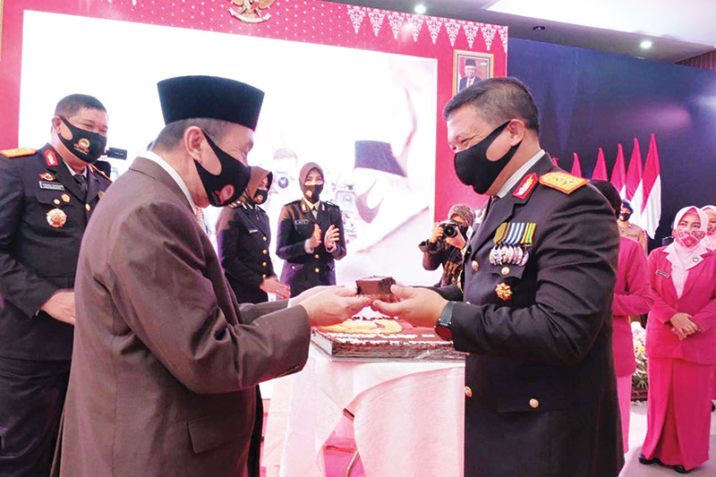 Kapolda Riau Irjen Pol Agung Setya Imam Effendi (kanan) menyerahkan potongan kue kepada Gubernur Riau Drs H Syamsuar MSi pada acara peringatan Hari Bhayangkara ke-74 di Aula Bhayangkara Mako Brimob Polda Riau, Pekanbaru, Rabu (1/7/2020). (HUMAS POLDA RIAU