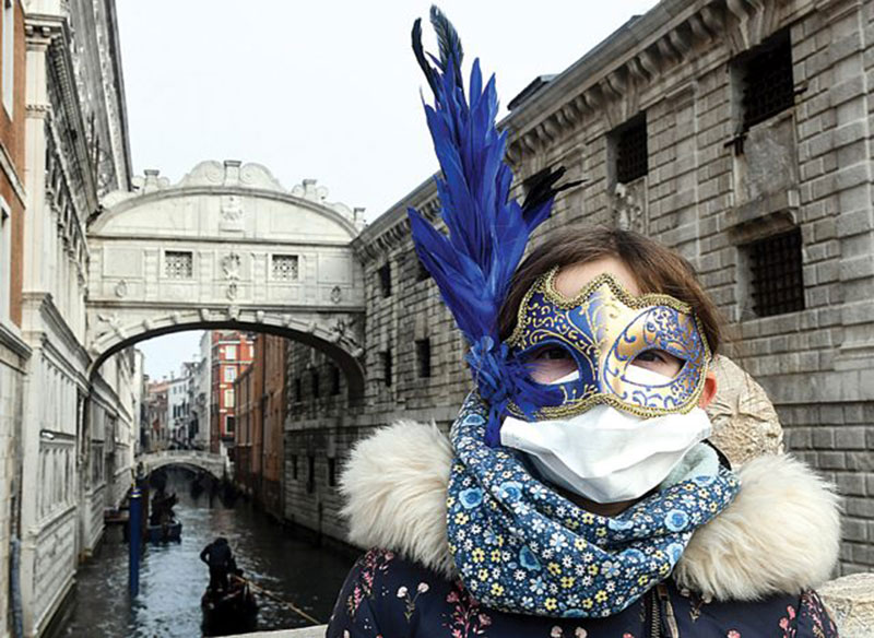 Masker pelindung yang dipakai turis di Venesia ini bukan peranti yang sepaket dengan topengnya. Senin (24/2), dia bermasker untuk mencegah penularan virus Korona (ANDREA PATTARO / AFP)