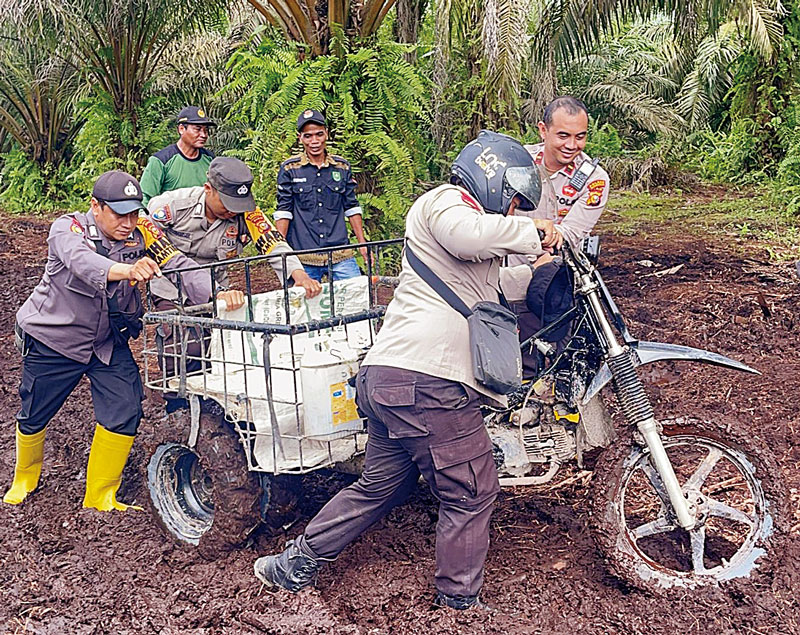 Kapolsek Siak Kecil Ipda Eko Wahyu NB SH MH mendorong motor grandong saat melewati lumpur gambut saat menuju Desa Tanjung Damai, Siak Kecil, Bengkalis, beberapa waktu lalu.