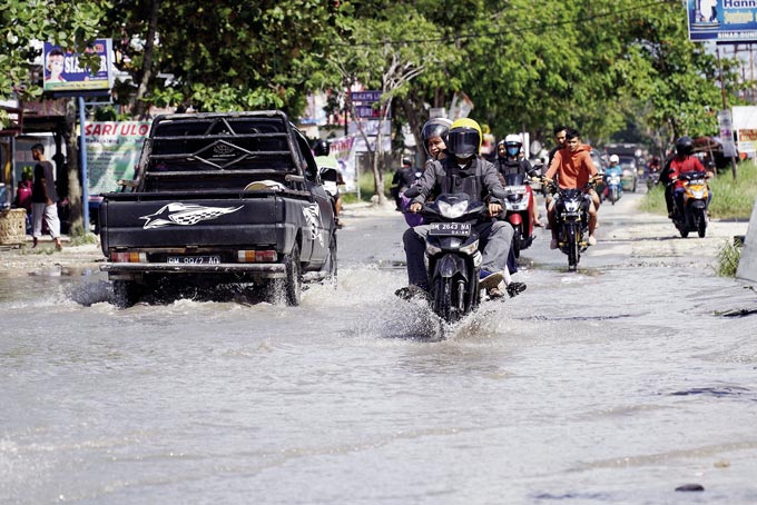 Kendaraan bermotor melintas di Jalan Darma Bakti, Kecamatan Payung Sekaki yang tergenang, Kamis (16/12/2021) siang.
