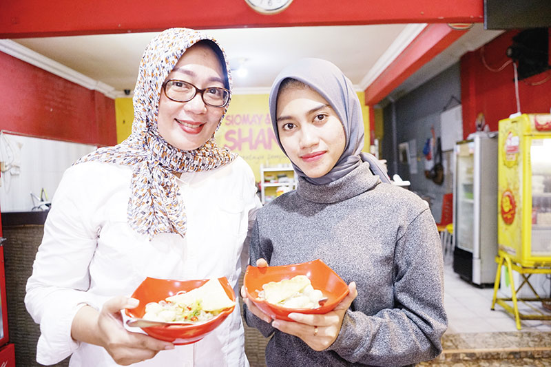 Perlihatkan menu: Host Makan Yuk Syahra Regina (kanan)  bersama dengan Hanny Shanaya selaku owner memperlihatkan menu Sotindang di Siomay dan Batagor Shanaya di Jalan Lobak, Nomor 109 C, Kota Pekanbaru, Selasa (24/12/2019).(siti azura/riau pos)
