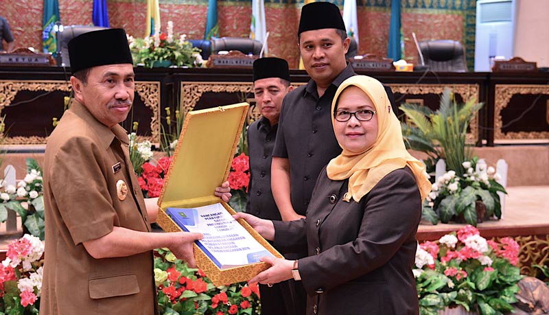 SERAHKAN RAPERDA: Gubri Syamsuar menyerahkan Ranperda Pertanggungjawaban Pelaksanaan APBD Provinsi Riau TA 2018 oleh Kepala Daerah kepada Ketua DPRD Septina Primawati di ruang paripurna gedung DPRD Riau, Kamis (13/6/2019).