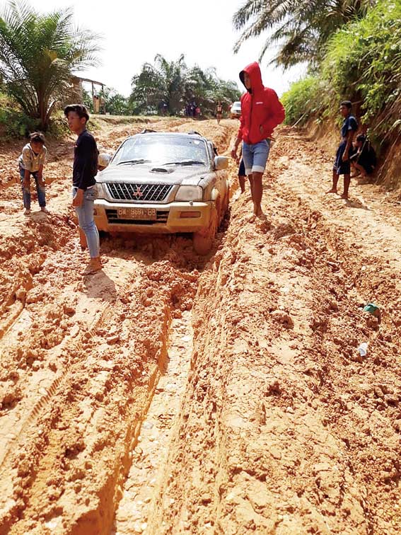 TERPURUK:  Satu unit mobil terpuruk di jalan rusak yang ada di Kecamatan Batang Cenaku. Beberapa titik jalan rusak terus terjadi saat musim hujan, Rabu (13/2/2019). (KASMEDI/RIAU POS)