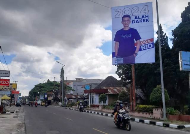 Baliho berukuran 4x6 meter menampilkan gambar Uda Rio, seorang influencer yang sedang naik daun, mengenakan kaos Tangkelek dengan tulisan â€œ2024 ALAH DAKEKâ€ terpasang di Kota Padang, pertengahan Juni 2023.