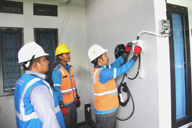 Petugas PLN memasang titik pengecasan mobil listrik di rumah salah seorang warga Pekanbaru, baru-baru ini.