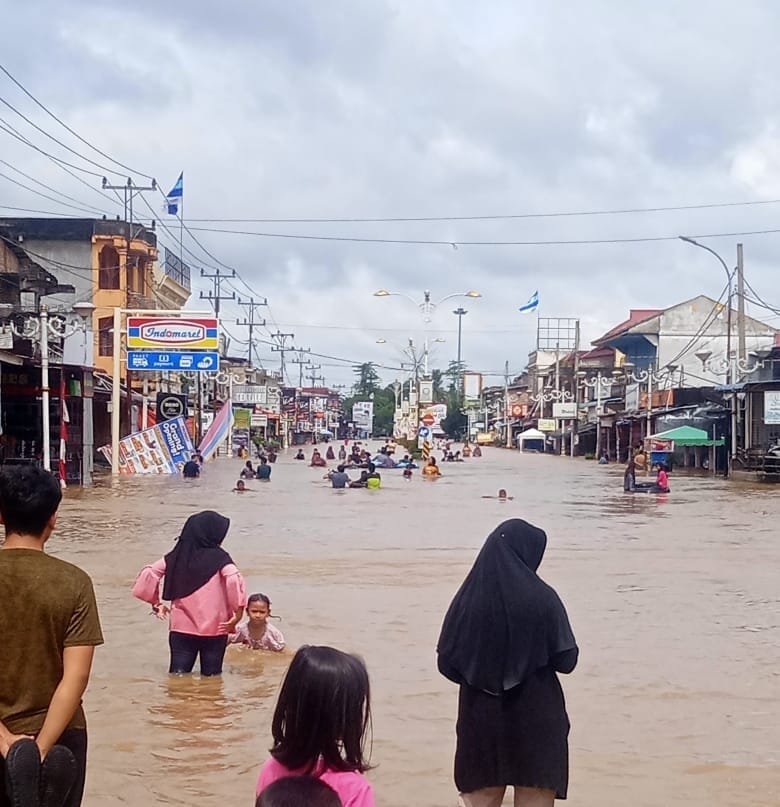 Masyarakat tampak bermain di genangan air banjir di Ruas Jalan Provinsi di Jalur dua Jalan Tuanku Tambusai, Dusun Nogori, Desa Babussalam, Kecamatan Rambah, Rabu (27/12/2023).