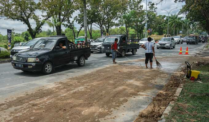 Beberapa pekerja memÂ­bersihÂ­kan ceceran sisa tanah timbun yang mengotori Jalan Jenderal Sudirman, samping Rumah Makan Koki Sunda, Senin (3/4/2023). Pembersihan ini dilakukan setelah petugas DLHK Pekanbaru turun ke lokasi memberikan teguran terhadap akti