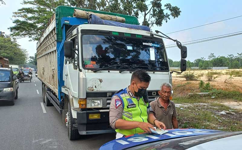 Petugas Satlantas Polresta Pekanbaru memberikan surat tilang kepada pengemudi truk yang melintas di Jalan Tuanku Tambusai, Jumat (28/1/2022).