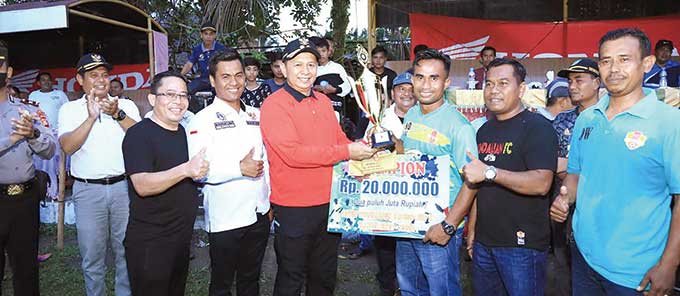 Wabup Rohul H Indra Gunawan didampingi Ketua Askab PSSI Rohul Buman Lubis (kemeja putih) menyerahkan trofi dan uang pembinaan kepada Manajer Pendalian FC sebagai juara turnamen Kades Cup II Desa Tandun dalam acara penutupan di lapangan sepakbola Simarak M
