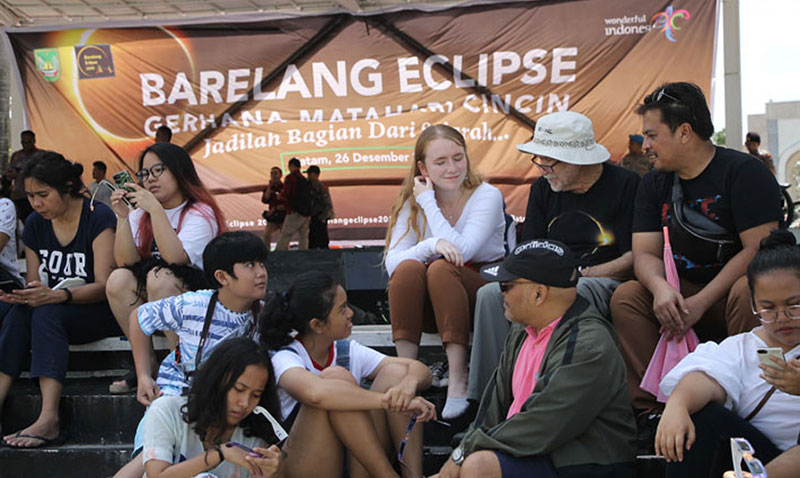 BERSAMA ANAK: Pemburu gerhana asal California AS Bruce Webster (pakai topi putih) dan putrinya Maria Webster (baju putih), saat berbincang dengan wartawan usai menyaksikan gerhana matahari cincin di Dataran Engku Putri Batam Centre, Kamis (26/12/2019). (R
