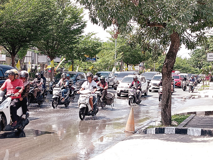 Pengendara kendaraan bermotor melewati genangan air di Jalan Jenderal Sudirman, Selasa (4/7/2023). Genangan air ini tak kunjung kering kendati cuaca panas.