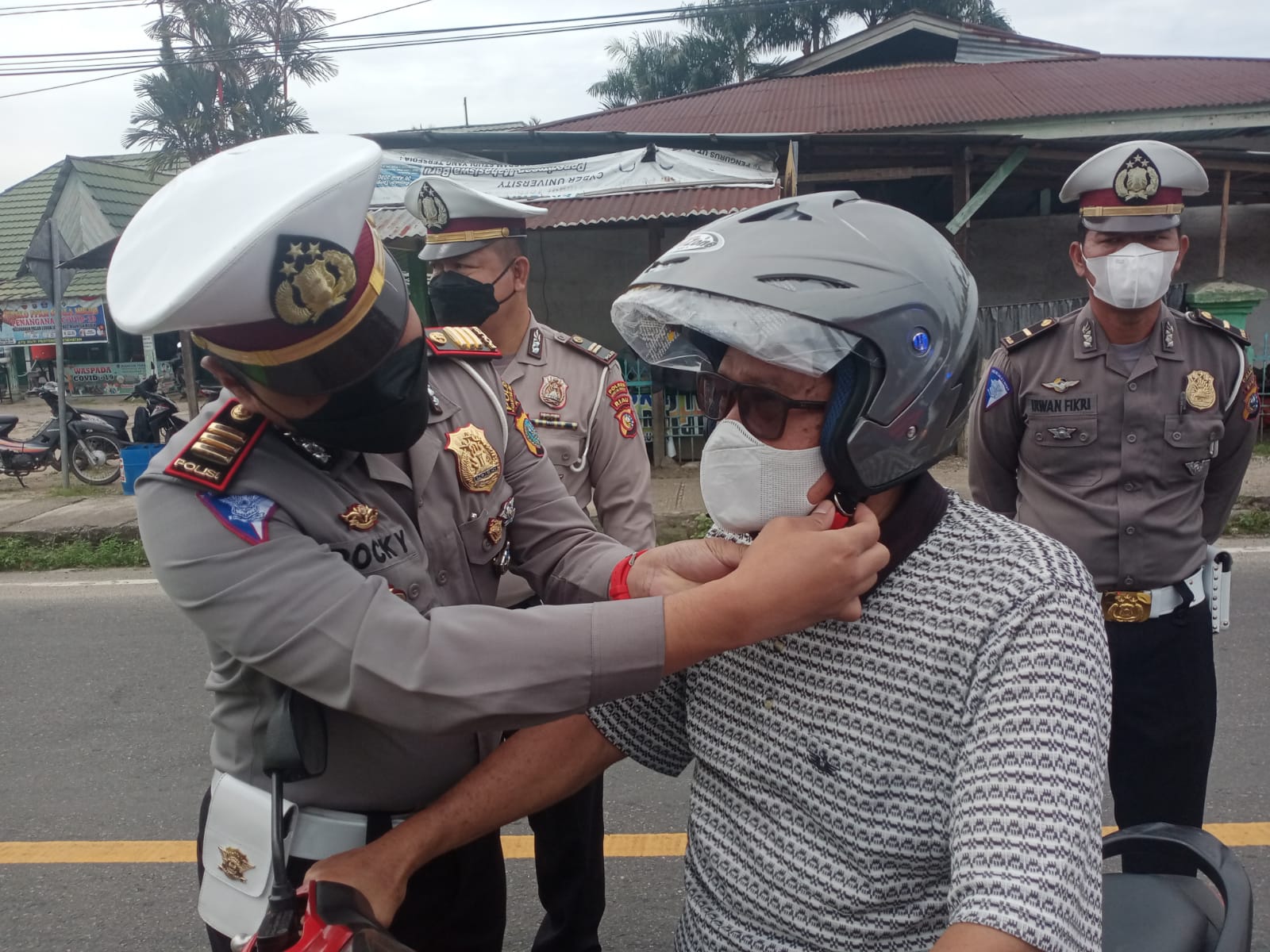 Kasat Lantas Polres Kuansing AKP Rocky Junasmi SIK MH memasang helm pada pengguna kendaraan bermotor di Kecamatan Kuantan Mudik, Jumat (29/10/2021).