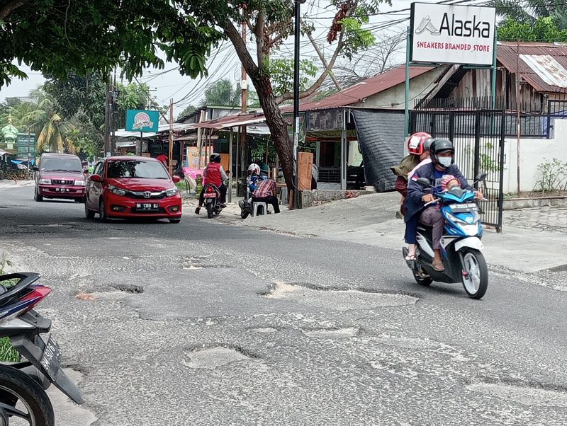 Pengendara sepeda motor menghindari lubang di badan Jalan Tengku Bey, Kecamatan Bukit Raya, Senin (18/9/2023).