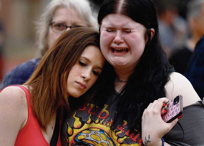 Brooklyn Deese (kiri) memeluk Alexa Keith saat mereka mengunjungi tugu peringatan penembakan para korban di Allen Premium Outlets, di Allen, Texas, Ahad (7/5/2023). Peringatan itu untuk para korban penembakan massal di Mal Allen Premium Outlets, Sabtu (6/