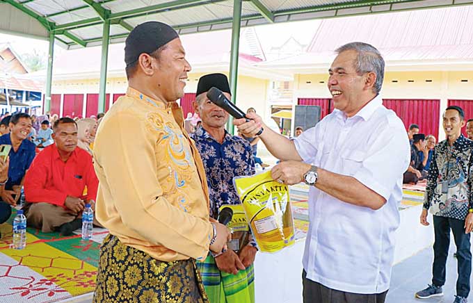 Pj Bupati Kampar Dr H Kamsol menyerahkan bantuan minyak goreng kepada warga saat meresmikan Pasar LKMD Desa Kasikan, Kecamatan Tapung Hulu, Kabupaten Kampar, Ahad (5/3/2023).
