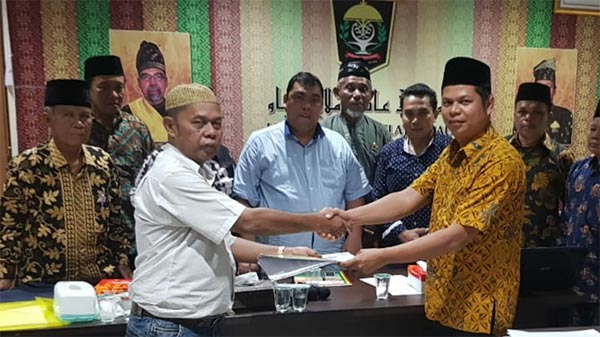 MENYERAHKAN: Ketua rapat yang juga Sekum LAMR, Nasir Panyalai memyerahkan SK MKA LAMR Kuansing kepada Pebri Mahmud di Pekanbaru, Kamis (4/7/2019).