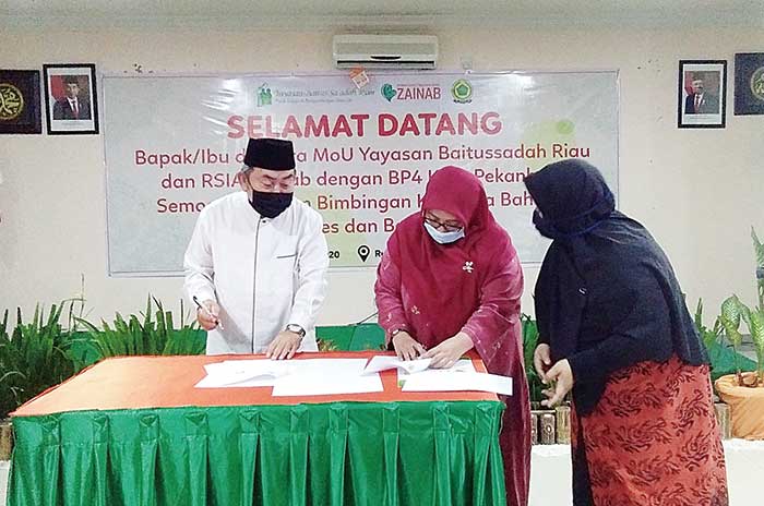 Ketua BP4 Pekanbaru Drs H Amirullah Hasyim (kiri) dan Ketua Dewan Pembina Yayasan Baitussaadah dr Diana Tabrani saat menandatangani perjanjian kerja sama, Jumat (19/6/2020). (MUJAWAROH ANNAFI/RIAUPOS.CO)