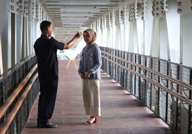 Ilustrasi petugas kesehatan memeriksa suhu badan penumpang LRT di Stasiun LRT Velodrome. (Dery Ridwansah/JawaPos.com)