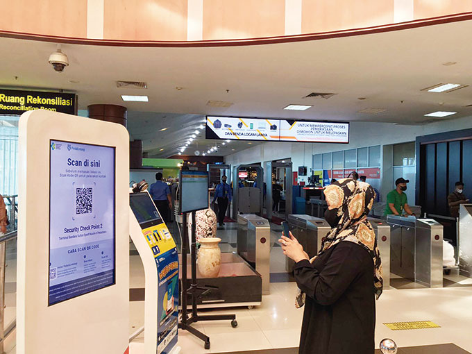 Calon penumpang memindai barcode PeduliLindungi di Bandara Sultan Syarif Kasim II Pekanbaru, Ahad (17/7/2022).