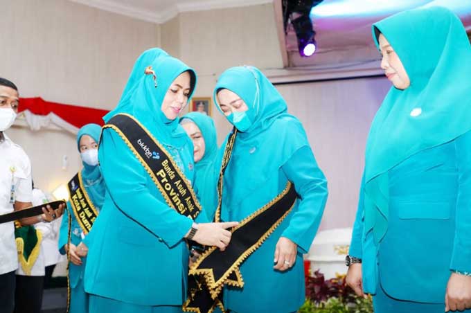 Ketua TP-PKK Provinsi Riau yang juga Bunda Asuk Anak Stunting Riau Hj Misnarni Syamsuar memakaikan selempang kepada Ketua TP PKK Siak yang juga Bunda Asuk Anak Stunting Kabupaten Siak di aula Serindit Gedung Daerah Riau, Pekanbaru pada Rabu (16/11/2022).
