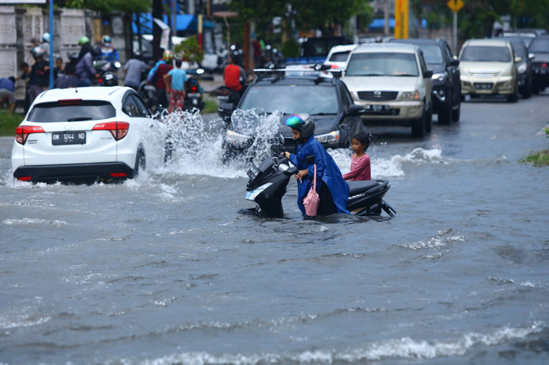 Pengendara roda dua mendorong kendaraan miliknya yang mogok saat berusaha melewati banjir di  Jalan Riau, Jumat (25/9/2020). Kawasan ini kerap menjadi langganan banjir setiap hujan deras turun. (EVAN GUNANZAR/RIAUPOS.CO)
