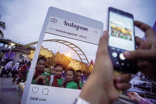 FESTIVAL: Sejumlah remaja putri berfoto dengan latar belakang Jembatan Siak III yang merupakan salah satu ikon Kota Pekanbaru dalam kegiatan Festival Sungai Siak 2018, Sabtu (15/12/2018). Festival Sungai Siak ini diharapkan dapat membangkitkan potensi wis