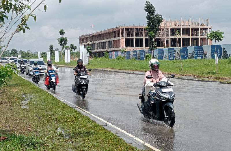 Pengendara motor berhati-hati saat melintas di Jalan Sembilang Rumbai yang masih digenangi air akibat buruknya sistem drainase sekitar, Kamis (14/12/2023).