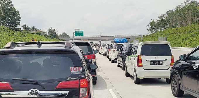 Puluhan kendaraan roda empat harus antre ketika akan melewati pintu keluar Tol Pekanbaru-Bangkinang, Ahad (25/12/2022). Kemacetan terjadi karena banyak pengendara yang baru membeli e-tol di pintu tersebut.
