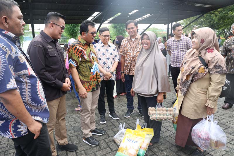 Region Head PalmCo Regional 3 Rurianto (batik hijau) didampingi Kepala Dinas Ketahanan Pangan Kota Pekanbaru Maisisco berbincang dengan masyarakat yang hadir dalam Gerakan Pasar Murah yang diselenggarakan di Kantor Pusat PalmCo Regional 3, Pekanbaru, belu