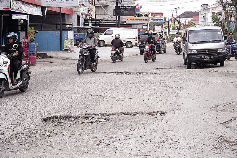 Pengendara kendaraan bermotor berusaha menghindari lubang-lubang di Jalan Paus, Kecamatan Marpoyan Damai, belum lama ini. Warga mendesak Pemko Pekanbaru untuk secepatnya memperbaiki Jalan Paus yang rusak parah.