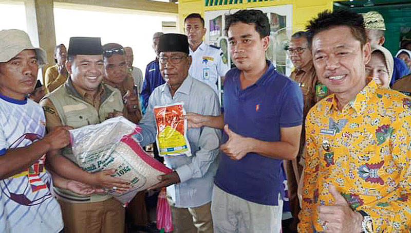 Kepala DKPP Rohil Aldi SIP (dua kiri) mendampingi Bupati Rohil Afrizal Sintong MSi (kanan) menyerahkan bantuan benih padi ke sejumlah kelompok tani di Kepenghuluan Bagan Punak Pesisir, Bangko, Selasa (7/11/2023).