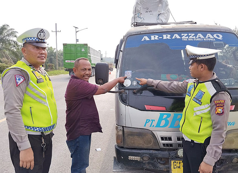 Personel Satgas Preemtif Ops Zebra Lancang Kuning 2023 memasangkan stiker di kendaraan umum di Jalinsum Riau-Sumut KM 167, Kelurahan Banjar XII, Kecamatan Tanah Putih, Rabu (6/9/2023).