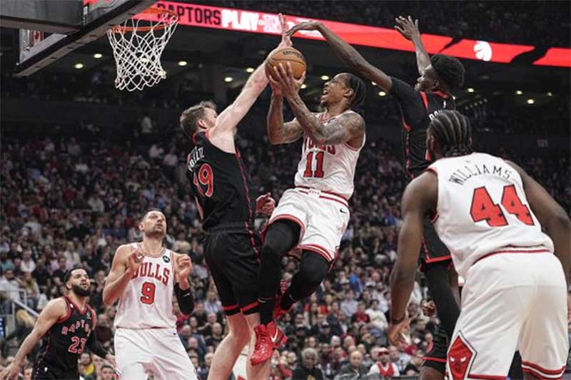 Center Toronto Raptors Jakob Poeltl (19) dan forward Chris Boucher (25) memblokir upaya tembakan forward Chicago Bulls DeMar DeRozan (11) selama pertandingan NBA Play-In di Scotiabank Arena, Kamis (13/4/2023).