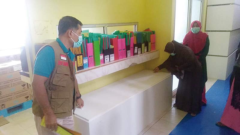 Kepala Diskes Kampar Dedy Sambudi (kiri) memeriksa peti jenazah Covid-19 yang disimpan di UPTD Farmasi Dinkes Kampar, baru-baru ini. (Hendrawan/RIAUPOS.CO)