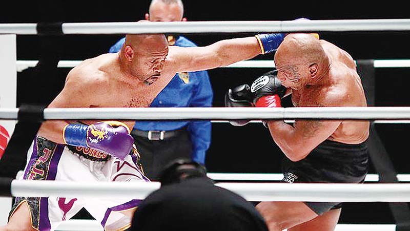 Dua legenda tinju Mike Tyson (kanan) dan Roy Jones Jr terlibat adu pukul dalam laga ekshibisi yang berakhir tanpa pemenang di Staples Center, Los Angeles, AS, Ahad (29/11/2020).(afp)