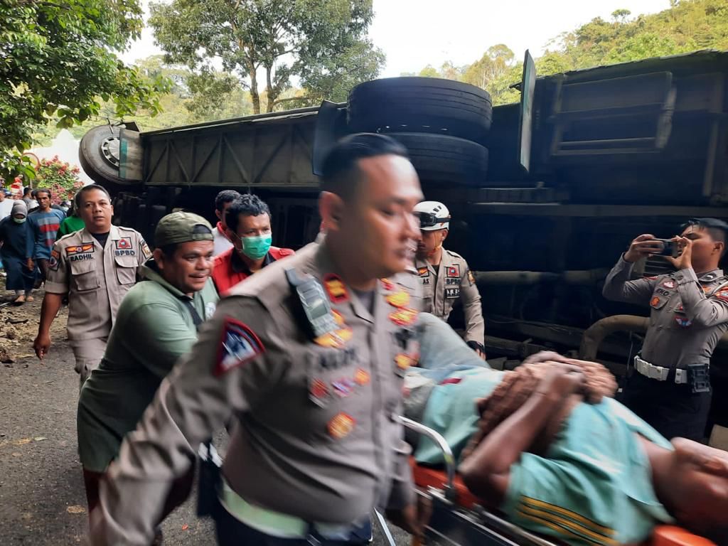 Pihak kepolisian dan warga melakukan evakuasi korban cedera dari kecelakaan bus mahasiswa Unri di Padang Panjang, Senin (19/12/2022).