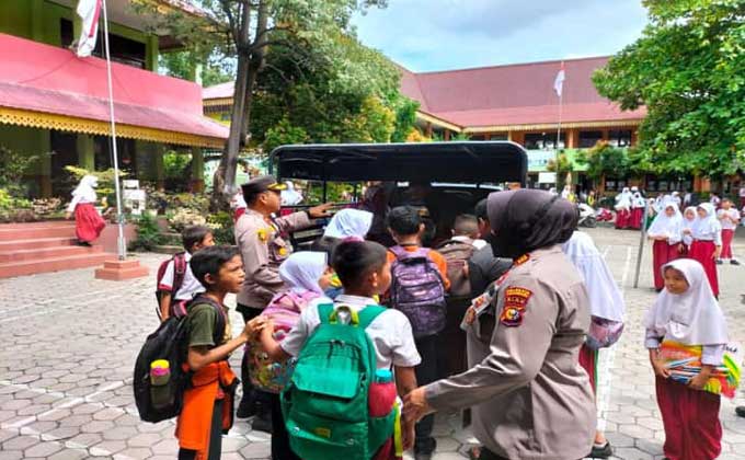 Murid SDN 002 dan SDN 003 antusias naik ke mobil patroli saat dijemput personel Polsek Senapelan untuk diantar pulang ke rumah masing-masing, Kamis (17/11/2022) siang.
