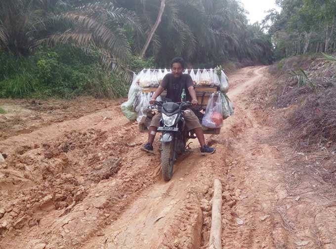 Pedagang sayur keliling kesulitan melintasi jalan utama Dusun Kuala 1, Desa Tanjung Air Hitam, Kecamatan Kerumutan yang rusak parah, Ahad (22/1/2023).