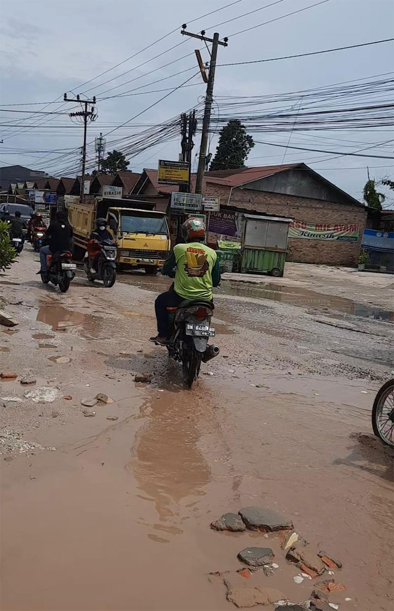 Warga saat melewati Jalan Suka Karya Desa Tarai Bangun, Kecamatan Tambang Kabupaten Kampar yang rusak parah, Rabu (8/11/2023).