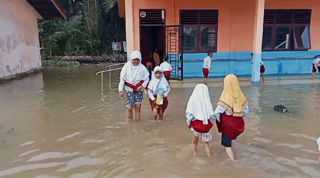 Sejumlah murid SDN 003 Bonai Darussalam melewati banjir saat menuju ruang kelas mereka di Desa Sontang, Kecamatan Bonai Darussalam, Rokan Hulu, Kamis (26/10/2023).