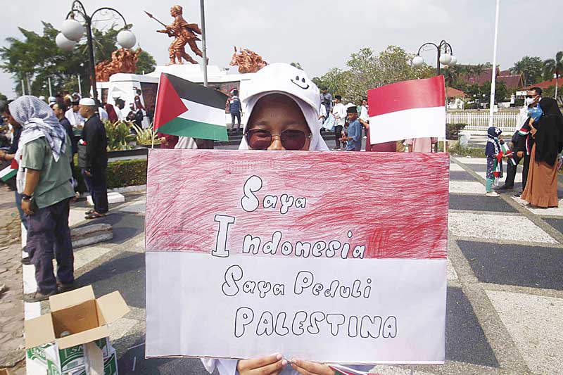 Salah seorang peserta aksi memperlihatkan poster dukungan terhadap Palestina di Tugu Perjuangan Rakyat, Jumat (13/10/2023).