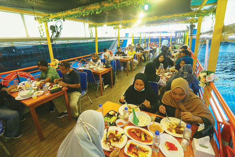Pengunjung menyantap hidangan sambil menikmati suasana pinggiran Sungai Siak di atas kapal Quantung Cruise, Ahad (18/10/2020). Kapal ini merupakan kapal restoran terapung pertama di Pekanbaru.(EVAN GUNANZAR/RIAUPOS.CO)