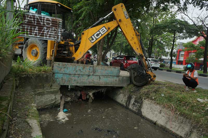 Dengan menggunakan alat berat, PUPR Kota Pekanbaru melakukan pengerukan endapan lumpur pada saluran air di Jalan Arifin Achmad, Selasa (18/7/2023). Jalan Arifin Achmad kerap terendam saat hujan turun karena aliran air tersumbat.