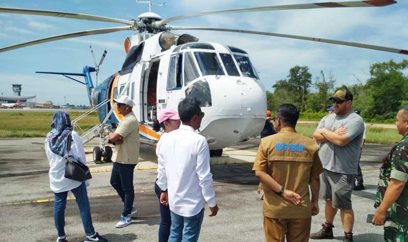 Perwakilan Badan Penanggulangan Bencana Daerah Riau berbincang dengan awak helikopter water bombing di Bandara SSK II Pekanbaru, Selasa (9/5/2023).