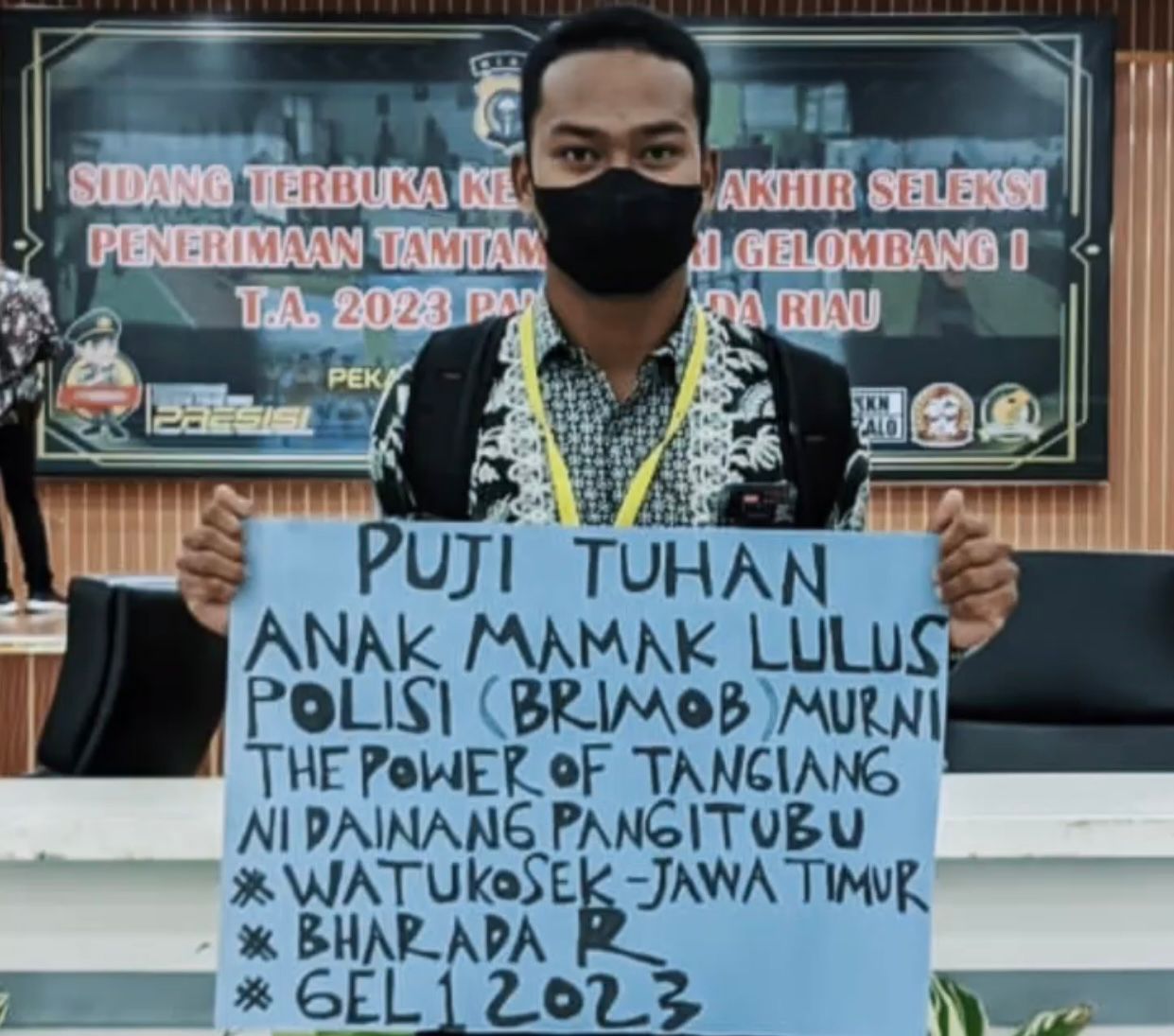 Rado Parasian Maruli Tua Simanjuntak membentangkan sebuah baner karton usai dinyatakan lulus menjadi anggota Polri, baru-baru ini.