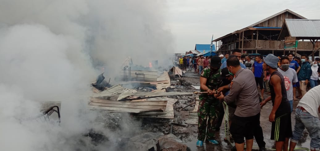 Petugas dibantu masyarakat memadamkan sisa api yang membakar puluhan lapak PKL di Sungai Guntung, Kecamatan Kateman, Inhil, Rabu (30/12/2020).(INDRA EFFENDI / RIAUPOS.CO)