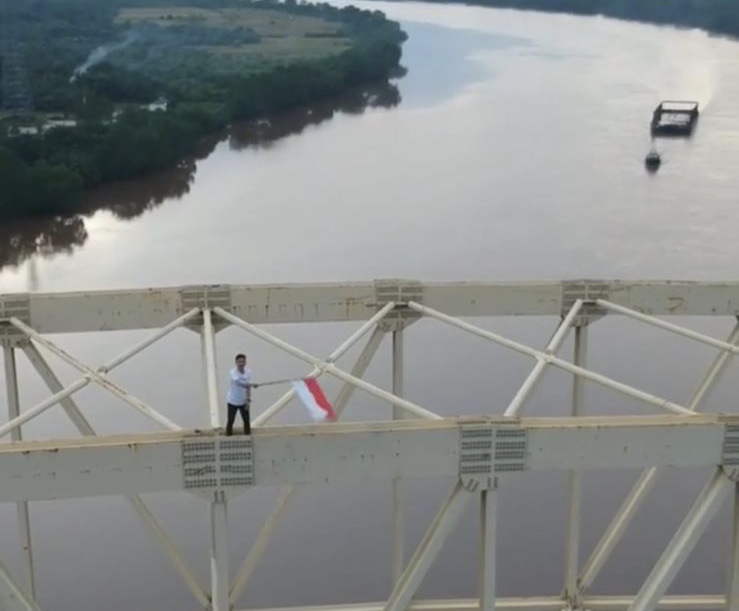 Tangkapan layar video viral Iska Saputra alias Cikoplur (30) mengibarkan bendera merah putih sambut hari kemerdekaan 17 agustus 2021 di jembatan Sultan Abdul Djalil Rachmad Syah Kampung Teluk Masjid, Kecamatan Sungai Apit, Kabupaten Siak.