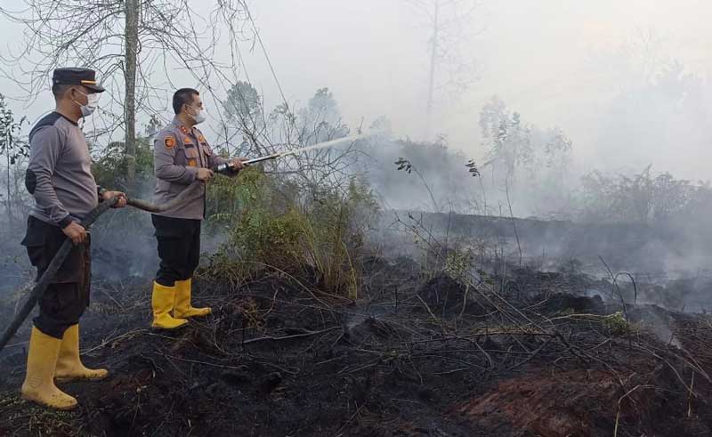 Kapolres Dumai AKBP Dhovan Oktavianton (kanan) memadamkan api yang membakar lahan di Jalan Simpang Sakel, Kelurahan Gurun Panjang, Kecamatan Bukit Kapur, Dumai, Rabu (2/8/2023).