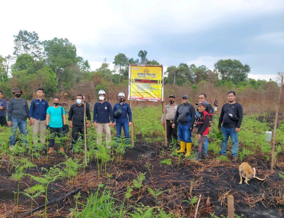 Petugas kepolsian saat berada di atas bekas lahan yang dibakar M.